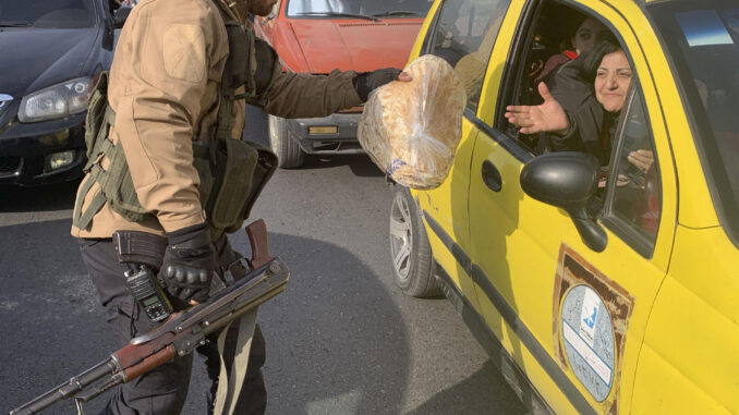 Un hombre armado entrega comida a una mujer este jueves en la Plaza de los Omeyas en Damasco, ciudad que vive unos días de transición tras la reciente caída del régimen de Bachar al Asad. EFE/Álvaro Mellizo
