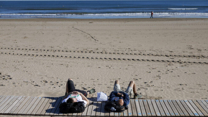 Dos personas disfrutan del buen tiempo en la playa de la Malavarrosa. EFE/Kai Försterling
