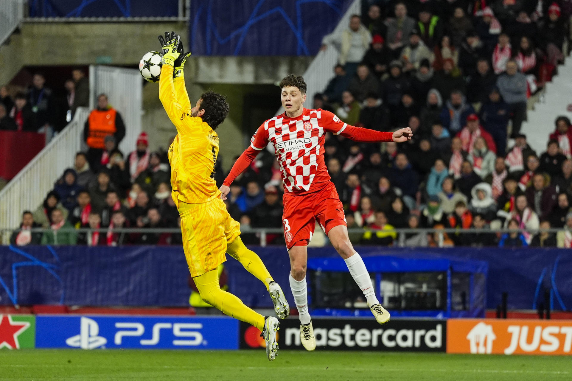 El portero del Liverpool Alisson Becker (izda) disputa el balón con el jugador del Girona FC Ladislav Krejci, durante el partido de Liga de Campeones disputado entre el Girona y el Liverpool, este martes en el estadio de Montilivi. EFE/Siu Wu
