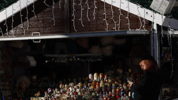 Una mujer camina junto a un puesto del mercadillo de Navidad en Ópera, Madrid, este jueves, en una mañana fría y soleada. EFE/ Mariscal
