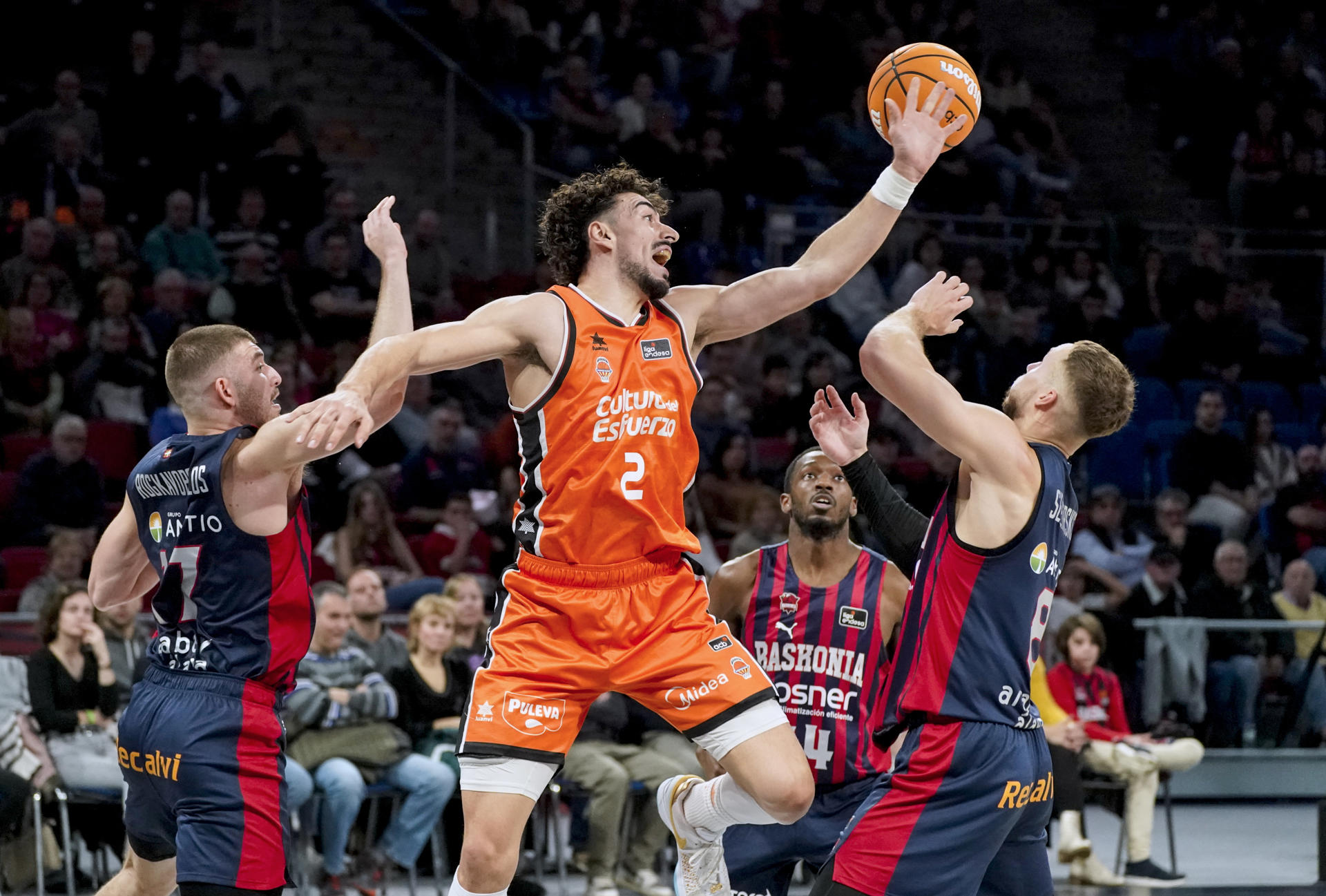 Los jugadores del Baskonia Nikos Rogkavopoulos (i) y Tadas Sedekerskis (d) y Josep Puerto (c) del Valencia, en acción durante el partido de Liga Endesa de baloncesto que se disputa este domingo en el Fernando Buesa Arena. EFE/L. Rico
