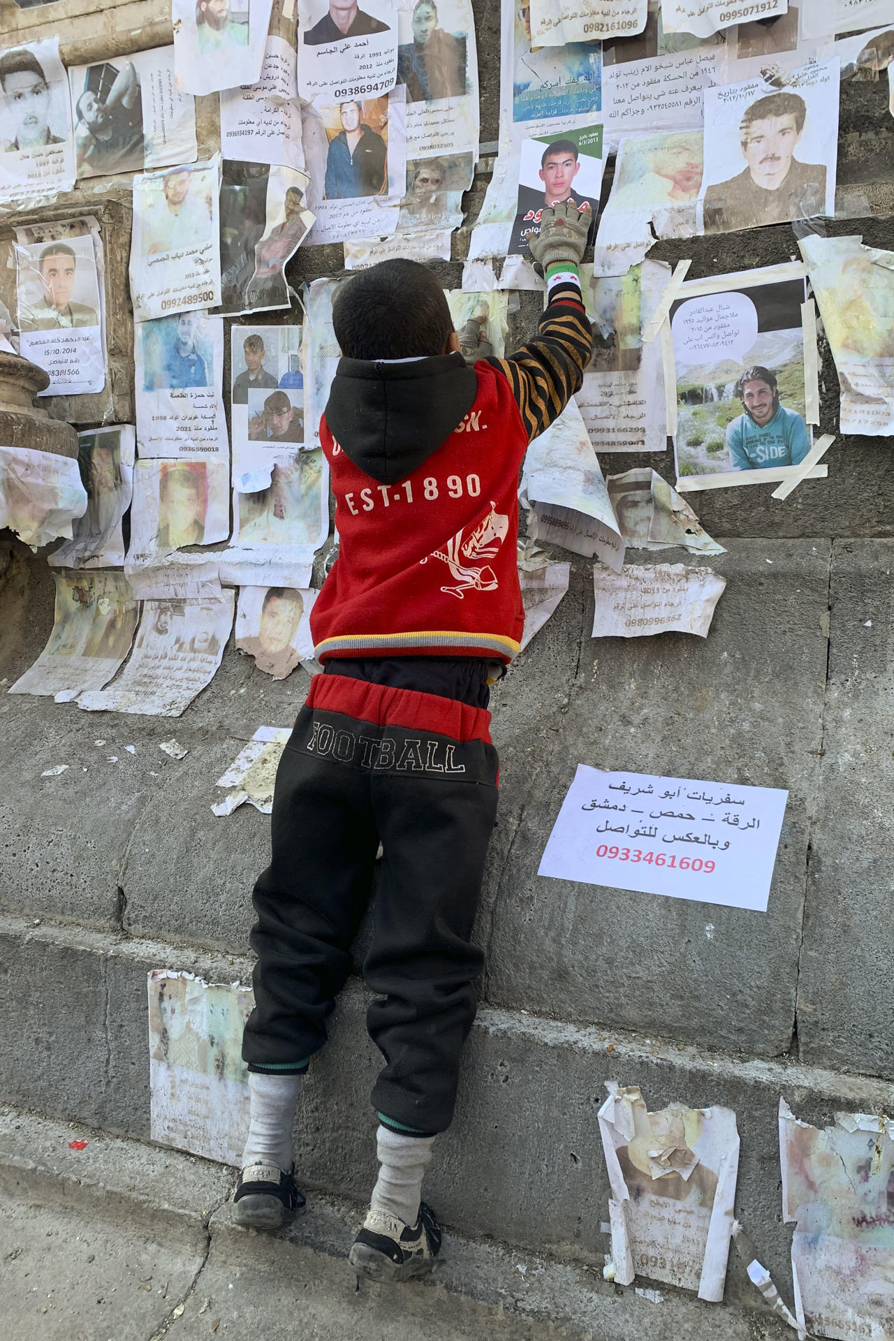 Un niño coloca una foto de un familiar aún en paradero desconocido un mes después del derrocamiento del régimen sirio, este 7 de enero de 2025 en Damasco. EFE/ Noemí Jabois
