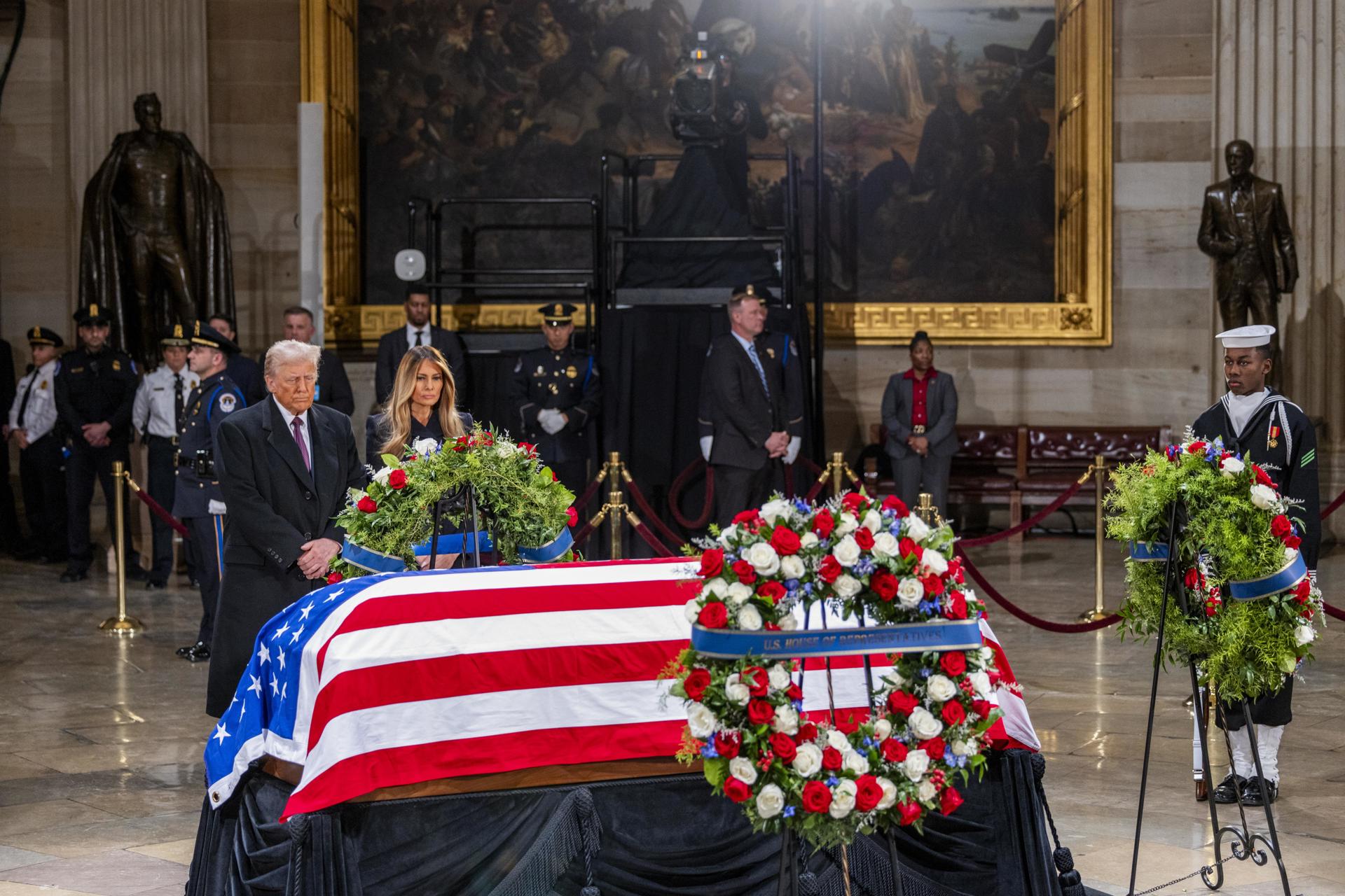 El presidente electo de Estados Unidos, Donald J. Trump, y Melania Trump se detienen ante el ataúd envuelto en la bandera del expresidente estadounidense Jimmy Carter mientras yace en la Rotonda del Capitolio de Estados Unidos en Washington, DC, EE. UU., el 8 de enero de 2025. EFE/EPA/Shawn Thew
