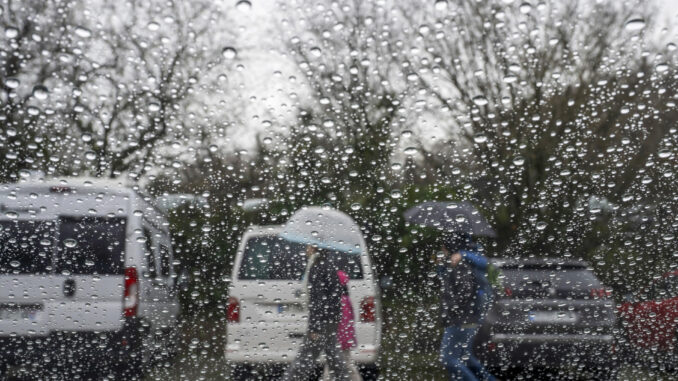 Varias personas caminan bajo la lluvia, este viernes, en la localidad cántabra de Santillana del Mar. EFE/Pedro Puente Hoyos
