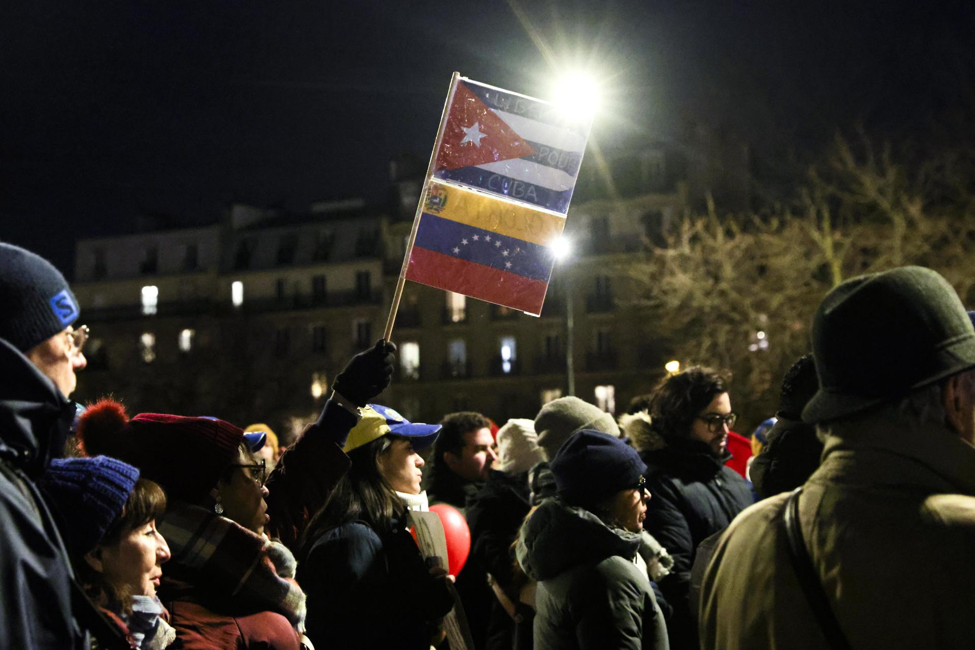 Una mujer sostiene una bandera cubana (arriba) y una venezolana durante una manifestación por la democracia en Venezuela, en la Plaza de la Bastilla en París, Francia, el 9 de enero de 2025. EFE/EPA/Teresa Suarez
