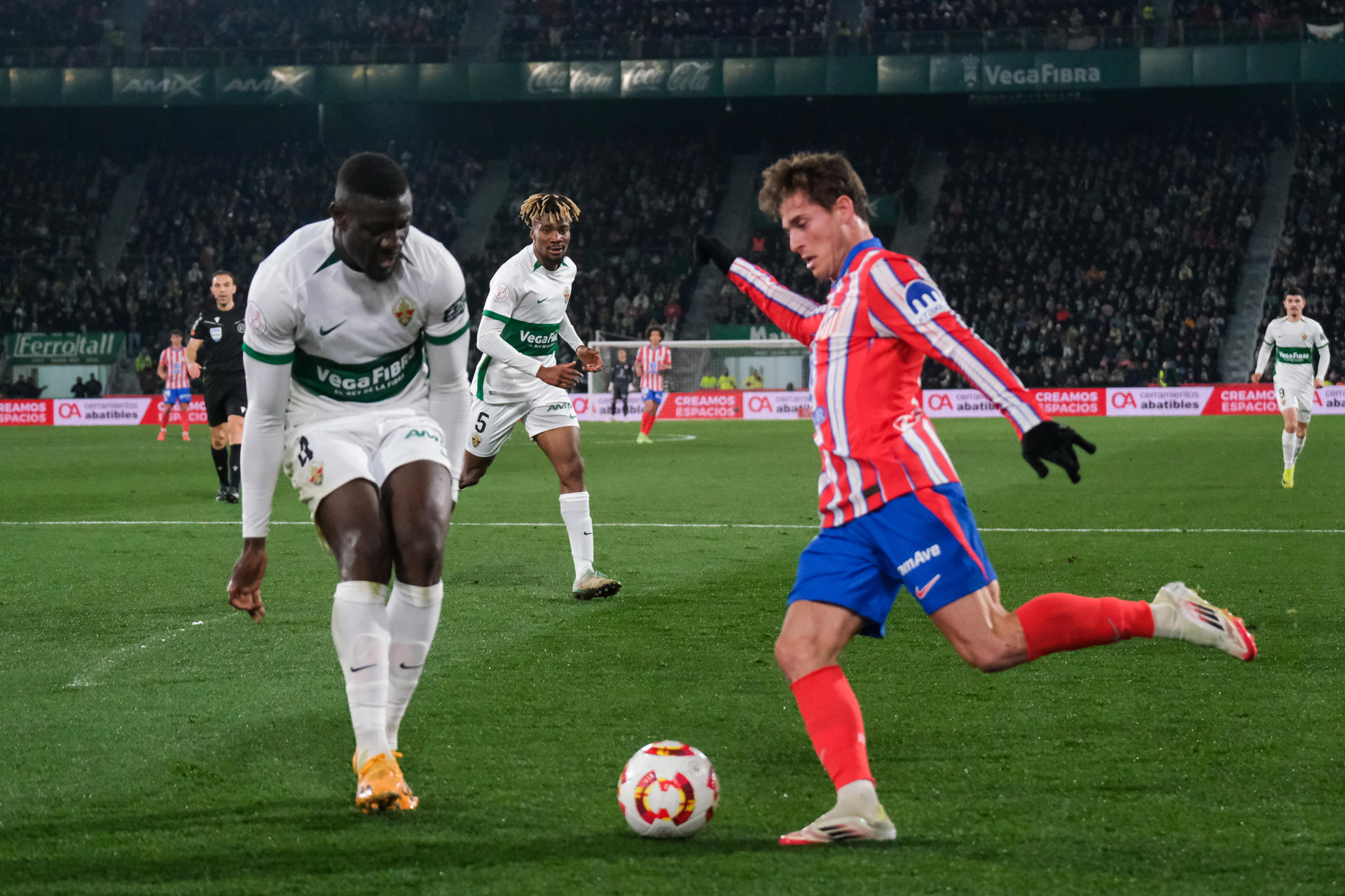 El centrocampista del Atlético de Madrid, Rodrigo Riquelme (d), con el balón ante el defensa del Elche, Bambo Diaby, durante el encuentro correspondiente a los octavos de final de la Copa del Rey en el Estadio Martínez Valero de la localidad alicantina. EFE / Pablo Miranzo.
