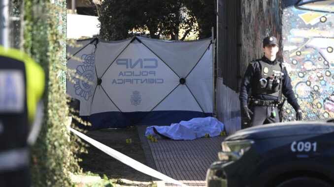 Un agente de la Policía Nacional junto al cuerpo de un hombre de unos 60 años, que ha aparecido muerto en la mañana de este lunes con heridas de arma de fuego en la localidad madrileña de Alcalá de Henares. EFE/ Fernando Villar
