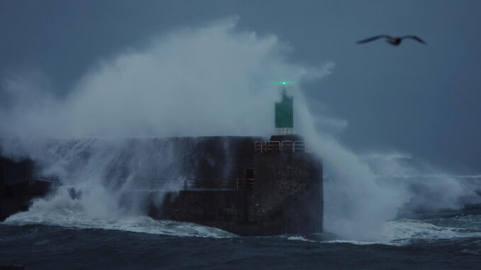 Una ola rompe contra el dique del puerto durante el temporal que azota la costa gallega este domingo en A Guarda, Pontevedra. EFE/Sxenick
