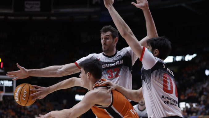 El ala pívot del Valencia Basket Jaime Pradilla (i) intenta superar a dos rivales del Covirán Granada en el partido de Liga Endesa de baloncesto que se disputó en la Fuente de San Luis, en Valencia. EFE/ Kai Forsterling
