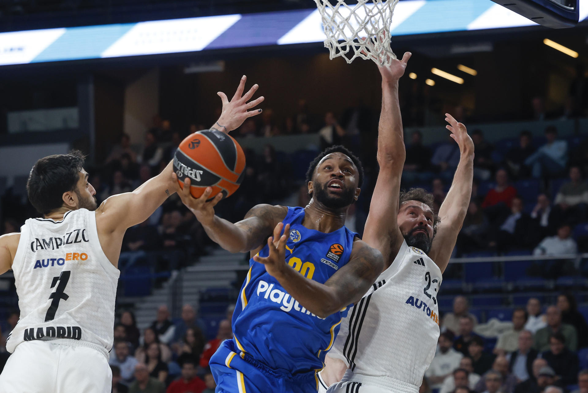 El ala-pivot estadounidense del Maccabi Levi Randolph (c) entra a canasta ante los jugadores del Real Madrid, el argentino Facundo Campazzo (i) y Sergio Llull, durante el partido de la jornada 21 de la EuroLiga de baloncesto entre el Real Madrid y el Maccabi de Tel Aviv, este martes en la capital española. EFE/Juanjo Martín
