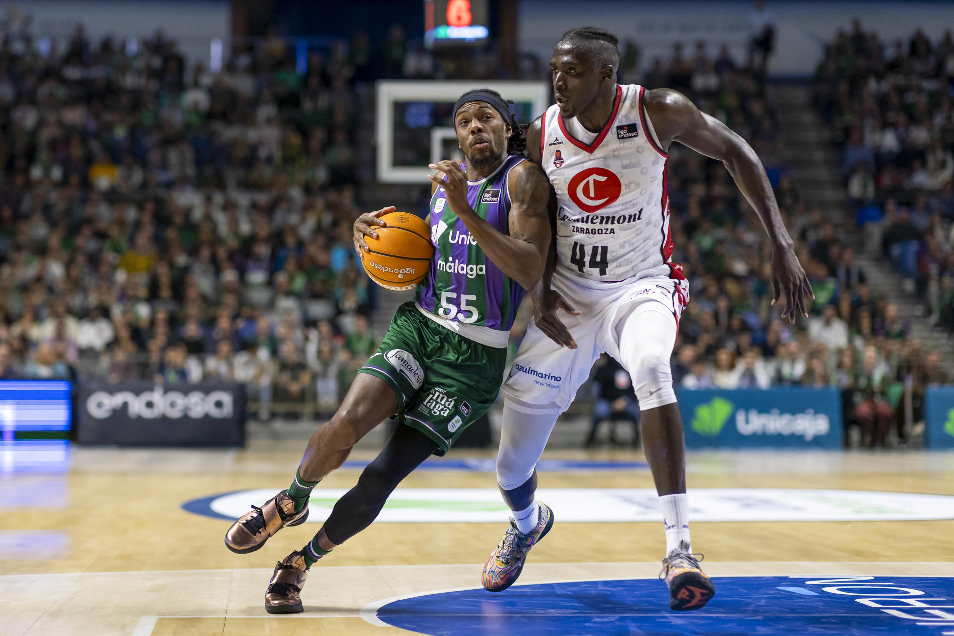 El base estadounidense del Unicaja, Kendrick Perry (i) entra a canasta ante el pívot angoleño del Casademont Zaragoza, Jilson Bango (d), durante el partido de la decimoquinta jornada de la liga Endesa disputado este sábado en el Palacio de Deportes José María Martín Carpena.- EFE/ Carlos Díaz
