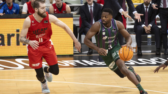 El alero nigeriano de Unicaja Melvin Ejim (d) controla el balón ante el escolta montenegrino de UCAM Murcia Nemanja Radovic (i), durante el partido de la décimo cuarta jornada de la liga Endesa que están disputando este jueves en el Palacio de los Deportes de Murcia. EFE/Marcial Guillén
