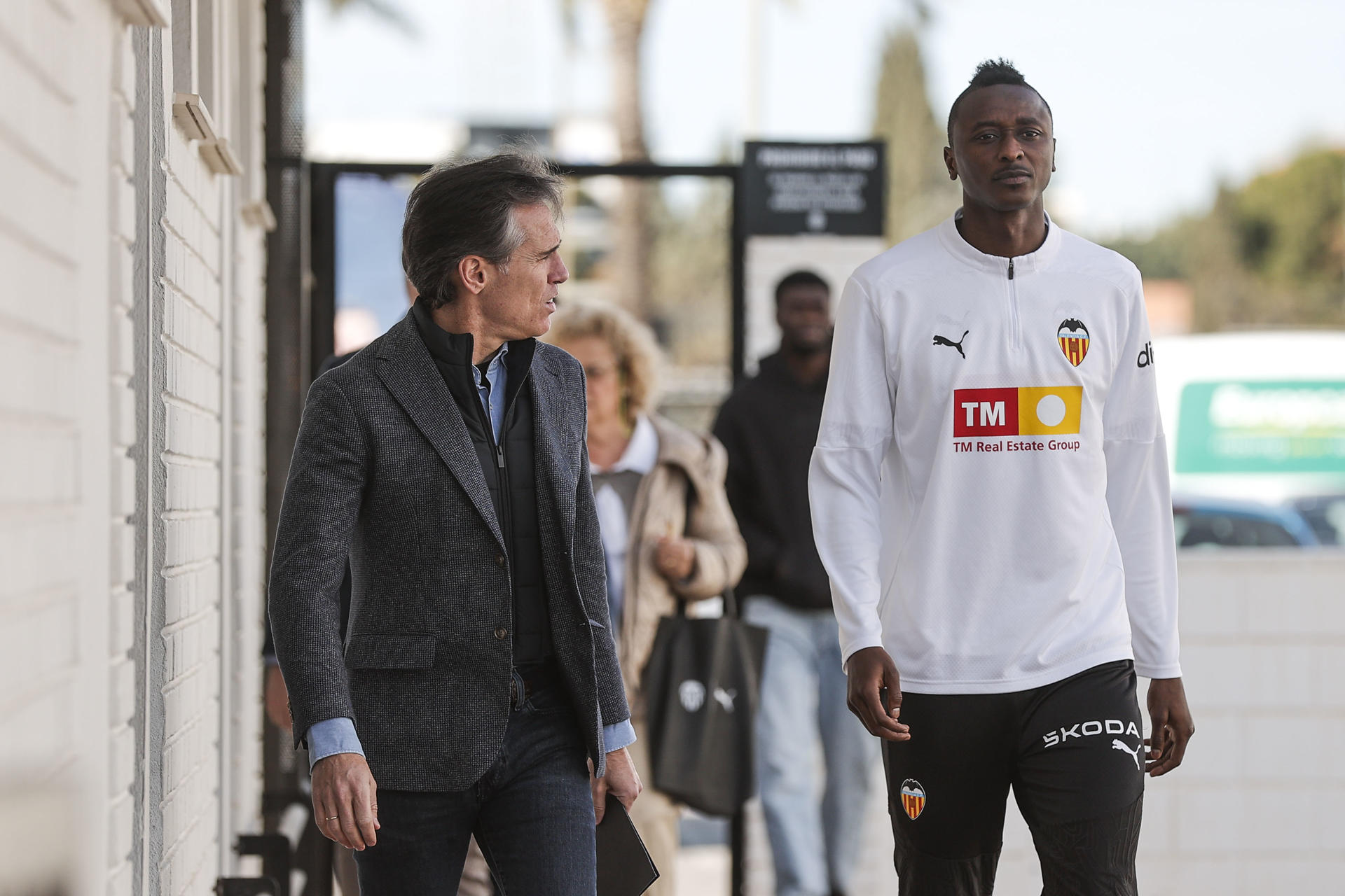 El delantero nigeriano Umar Sadiq se dirige, este sábado, a la rueda de prensa en la que ha sido presentado como nuevo jugador del Valencia, al que llega cedido de la Real Sociedad. En la imagen Sadiq junto al Miguel Ángel Corona, director deportivo del club. EFE/Manuel Bruque
