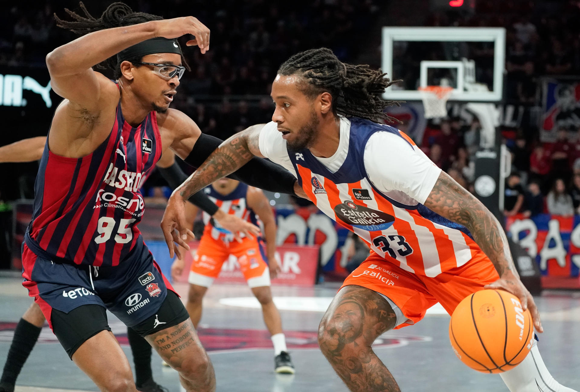 El ala pívot nigeriano de Baskonia Chima Moneke (i) defiende al pívot estadounidense del Leyma Coruña Trey Thompkins, durante el encuentro correspondiente a la fase regular de la Liga Endesa que disputaron frente a Leyma Coruña en el Fernando Buesa Arena de Vitoria. EFE / L. Rico
