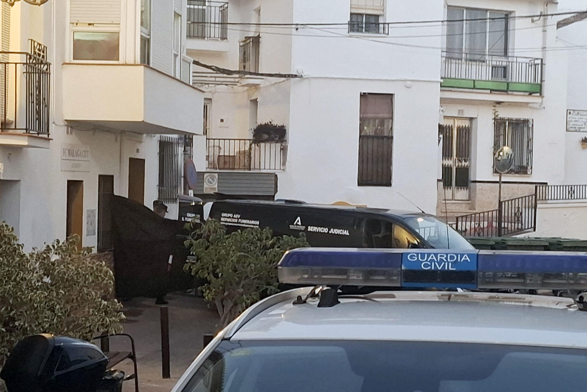 Coches de la Guardia Civil y de los servicios funerarios junto a la vivienda (izquierda) en Torrox (Málaga), donde este martes han fallecido cuatro personas de una misma familia por inhalación de gas según han informado a EFE fuentes municipales y de emergencias.EFE/Salvador Ruiz
