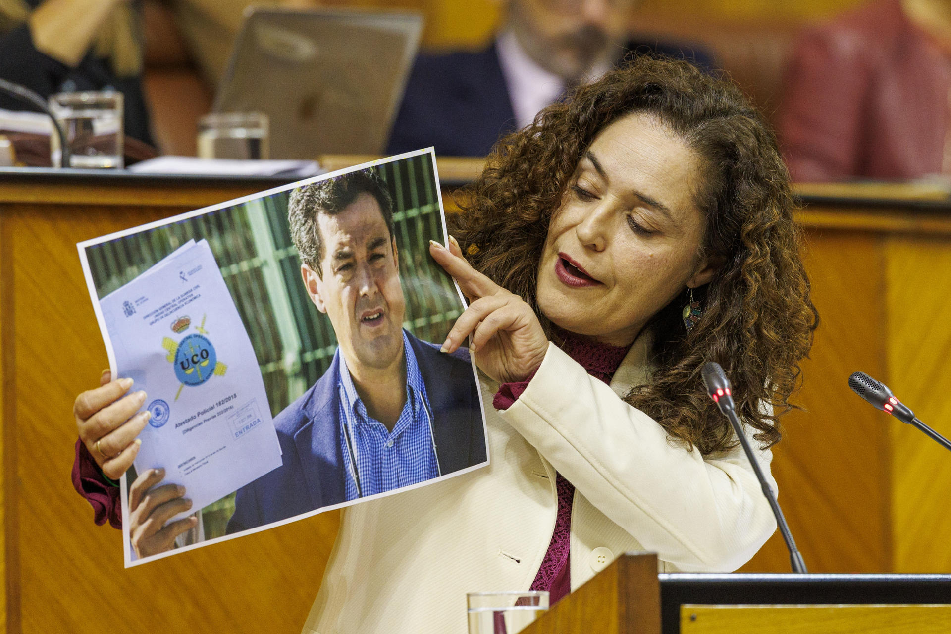La portavoz del grupo parlamentario Por Andalucía, Inmaculada Nieto, muestra una foto de Juanma Moreno y un informe de la UCO durante su intervención hoy jueves en el al Parlamento autonómico en Sevilla, que afronta el último debate sobre el estado de la comunidad de esta legislatura, a pocos meses de las elecciones andaluzas, previstas para el próximo mes de junio. EFE/Julio Muñoz
