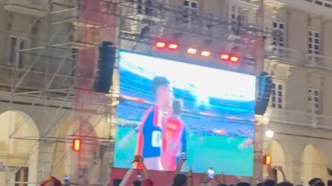 Multitud de personas celebrando en la Plaza María Pita de A Coruña durante la noche con pantallas LED mostrando contenido deportivo del Mundial de fútbol