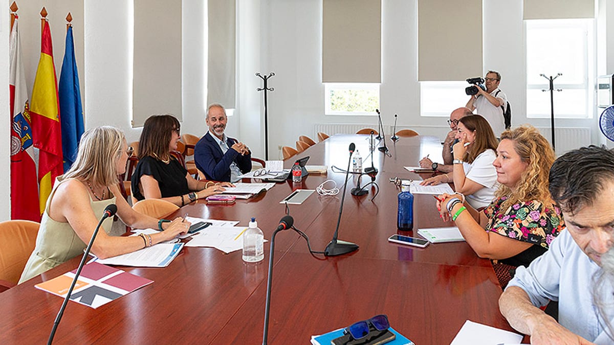 Reunión del Consejo de la Consejería de Educación de Cantabria con mesa de trabajo, banderas y documentación