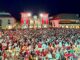 Plaza nocturna de Pinto llena de ciudadanos celebrando la victoria de España en la Copa Mundial de la FIFA 2026, con edificios iluminados de rojo y blanco