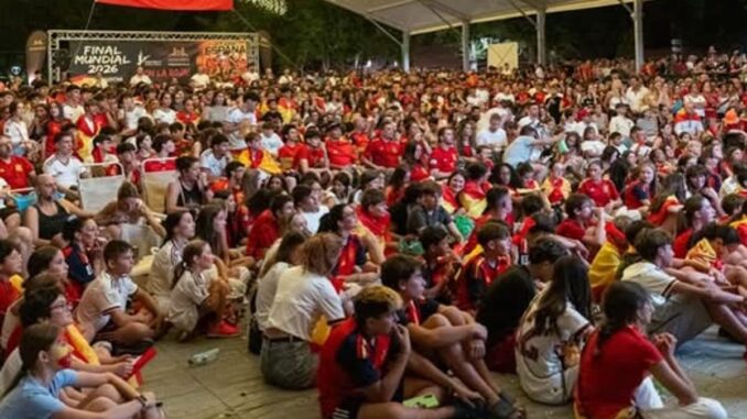 Concentración de vecinos en la Plaza de los Arcos de Sevilla la Nueva durante el minuto de silencio en memoria de Aysha, con la bandera de España visible de fondo