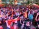 Multitud de personas celebrando en la Plaza de España de Tomelloso durante la noche, ondeando banderas rojas y amarillas
