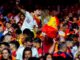 Multitud de aficionados en evento deportivo vistiendo equipos de fútbol en rojo, amarillo y blanco durante Copa Mundial FIFA