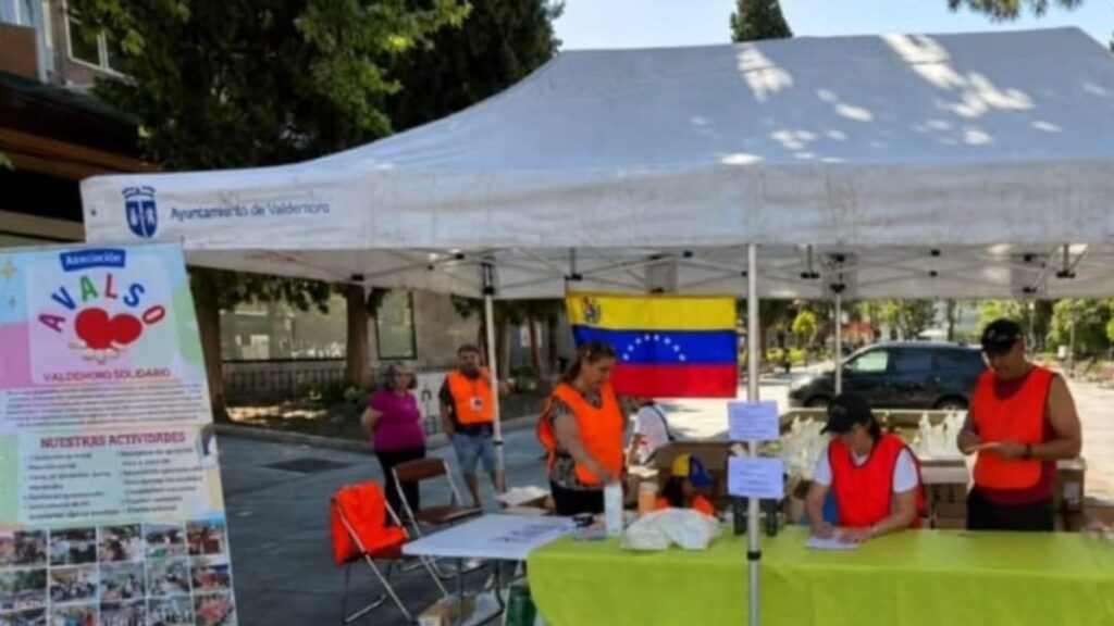 Cartel de campaña solidaria del Ayuntamiento de Valdemoro con logo de AVALSO y bandera de Venezuela en tienda local