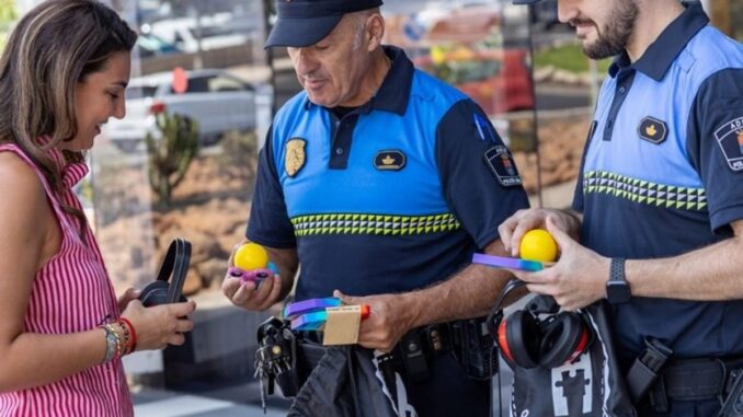 Tres personas en un entorno exterior con agentes de seguridad municipal y una mujer en vestido rosa