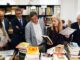 Grupo de personas en una biblioteca o sala de archivos examinando libros y documentos sobre una mesa