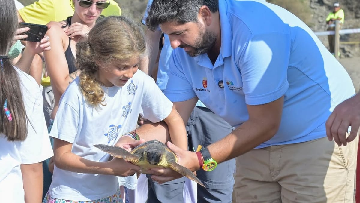 Evento de devolución de tortuga al mar en Lorca, con educador mostrando ejemplar a público en la Cala de Calnegre