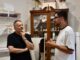Señorito Ortega conversando en su atelier con estanterías de textiles y productos artesanales