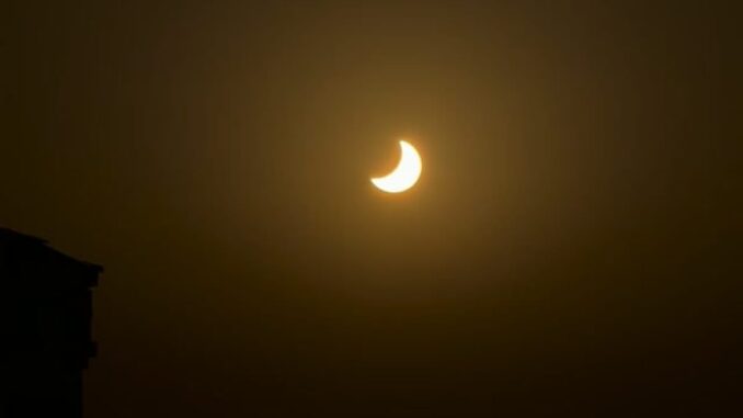 Un eclipse y atardecer tiñen el cielo de Cádiz Vista del eclipse y atardecer sobre el horizonte de Cádiz con tonalidades naranjas y rojas en el cielo