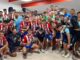 Grupo de jugadores de fútbol y personal de equipo posando en vestuario