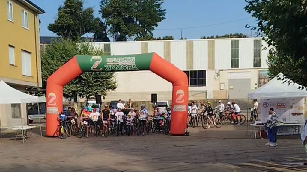 Salida de participantes en Iberlobo on Bike El Puente de Sanabria con arco inflable rojo de meta