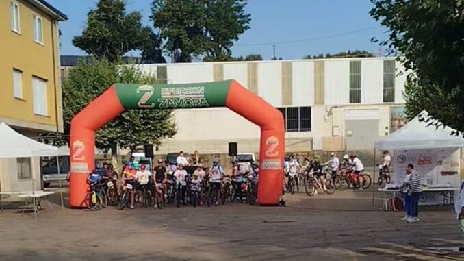 Salida de participantes en Iberlobo on Bike El Puente de Sanabria con arco inflable rojo de meta
