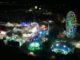 Vista aérea nocturna del recinto ferial de Pinto con rueda de la fortuna iluminada y atracciones coloridas