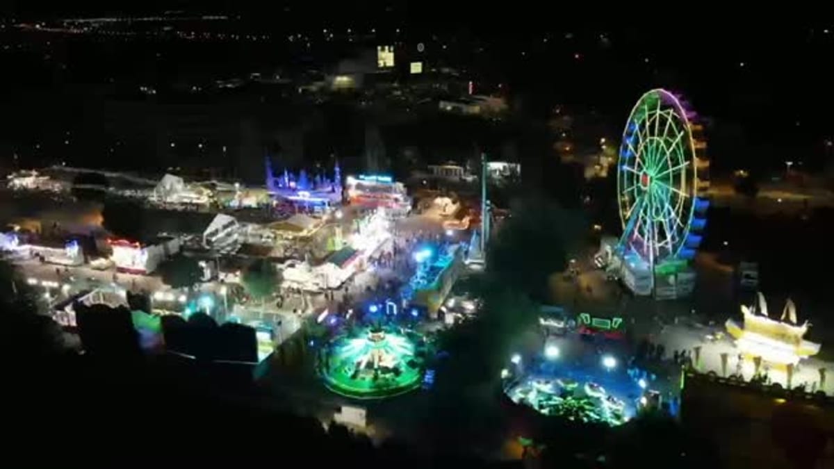 Vista aérea nocturna del recinto ferial de Pinto con rueda de la fortuna iluminada y atracciones coloridas