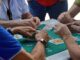 Grupo de personas jugando al mus alrededor de una mesa verde durante un torneo