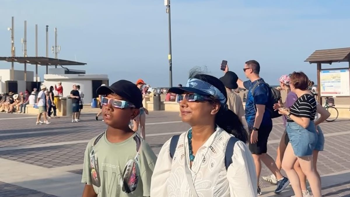 Personas observando el eclipse total de Sol en la playa de la Malvarrosa de Valencia con gafas de eclipse