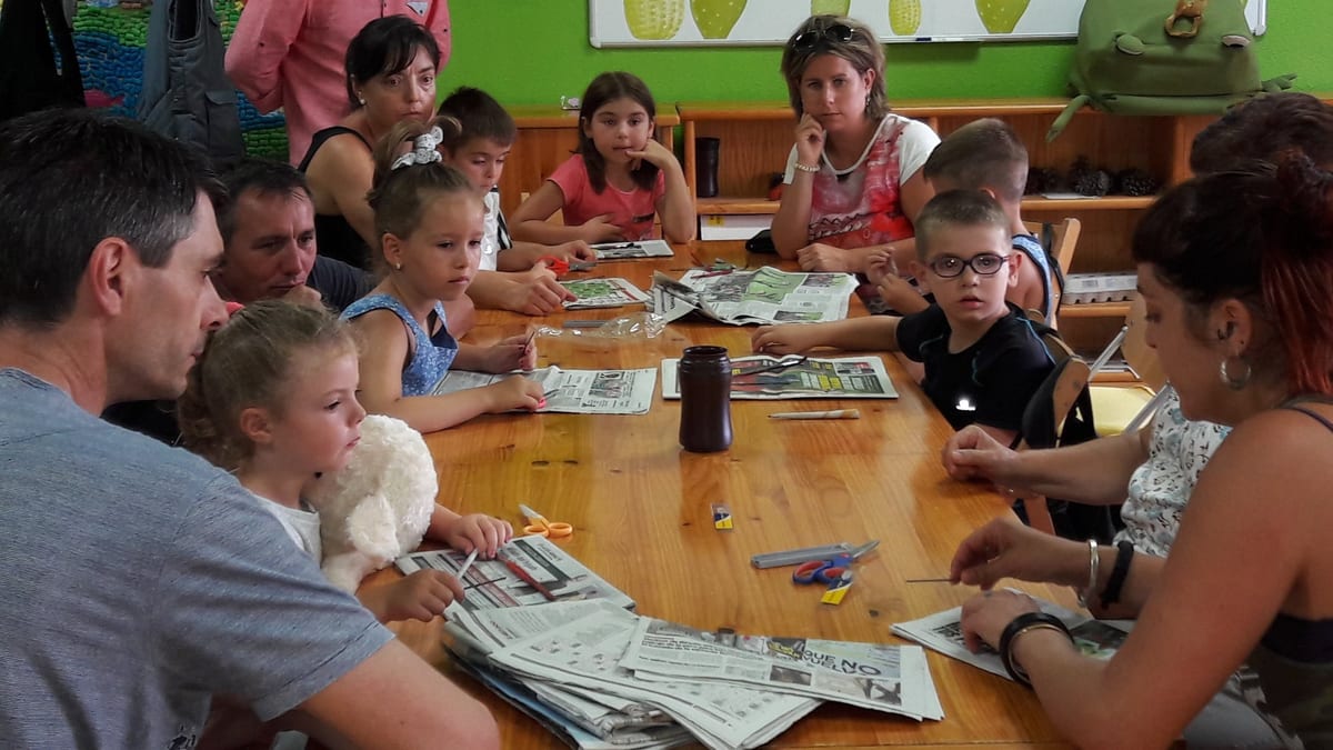 Grupo de niños y adultos en una actividad educativa del Aula Medioambiental de La Grajera trabajando con materiales didácticos