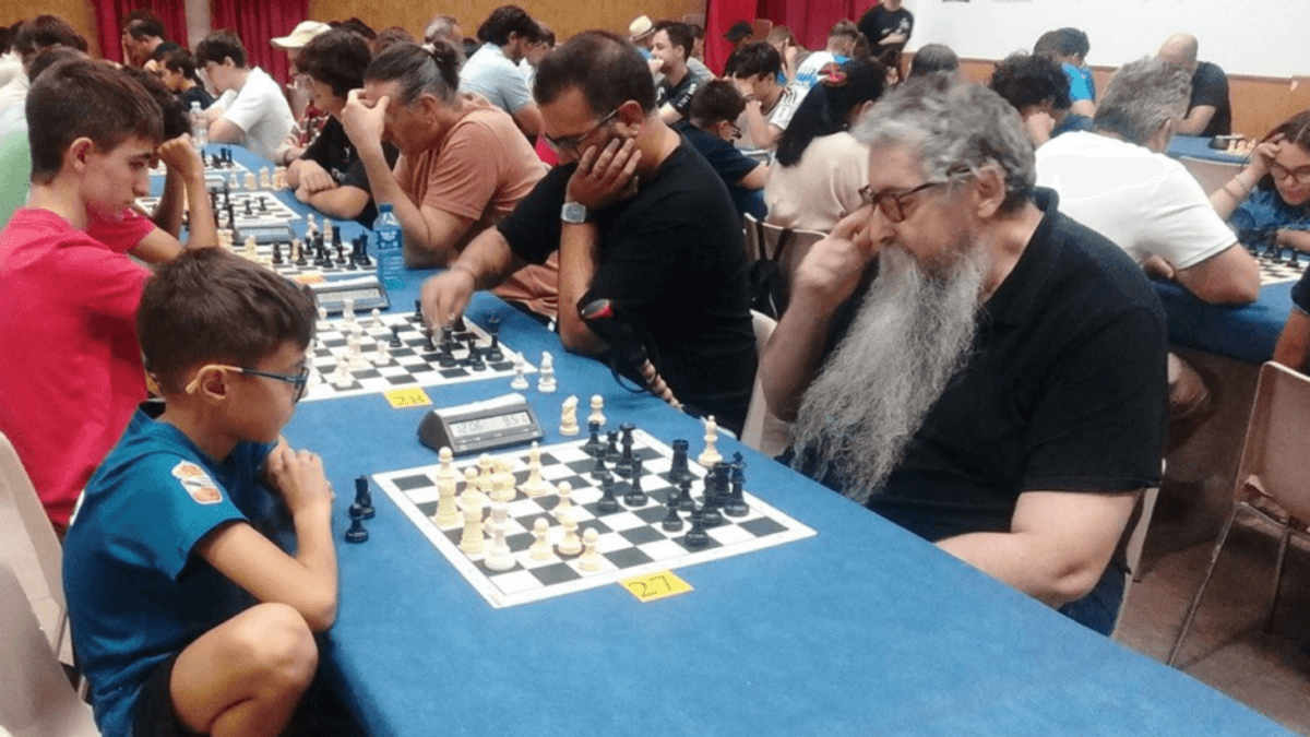 Escena del XXXVII Torneo de Ajedrez Diputación de Cáceres en Jarandilla de la Vera con múltiples participantes jugando simultáneamente en mesas azules
