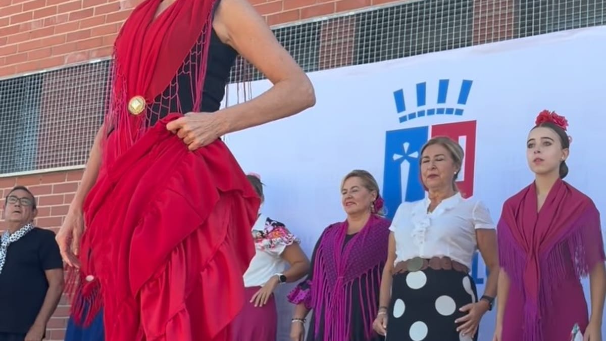 Mujer con vestido rojo en la IX Feria de las Asociaciones de Paracuellos de Jarama, con otras personas con trajes tradicionales de fondo