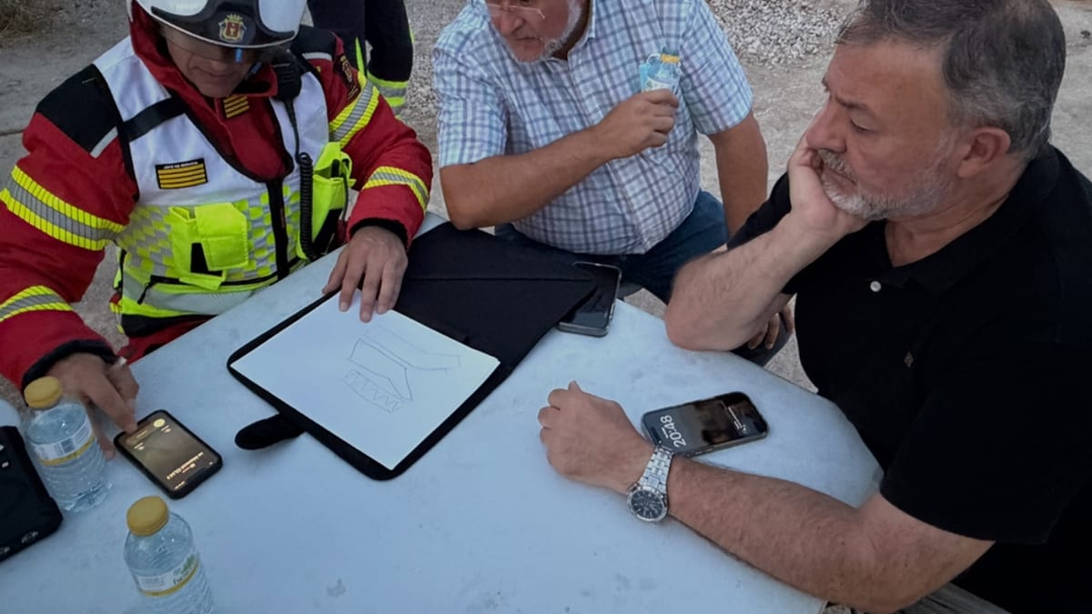 Equipos de emergencia trabajando en la extinción del incendio de MOBEC en Cuenca, revisando información en tableta en el lugar de la emergencia