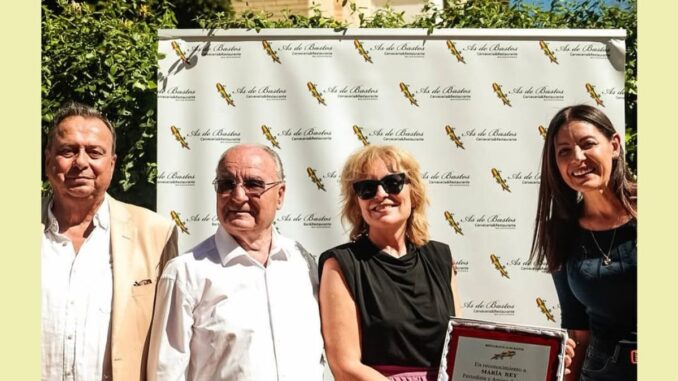 Celebra el 27º aniversario del As de Bastos en Majadahonda Representantes del As de Bastos sostienen placa conmemorativa del 27º aniversario durante las Fiestas de Majadahonda 2026