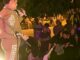 Performer en traje decorado actuando en el escenario del Parque Gallarza de Logroño durante la noche, frente a una audiencia bajo árboles iluminados