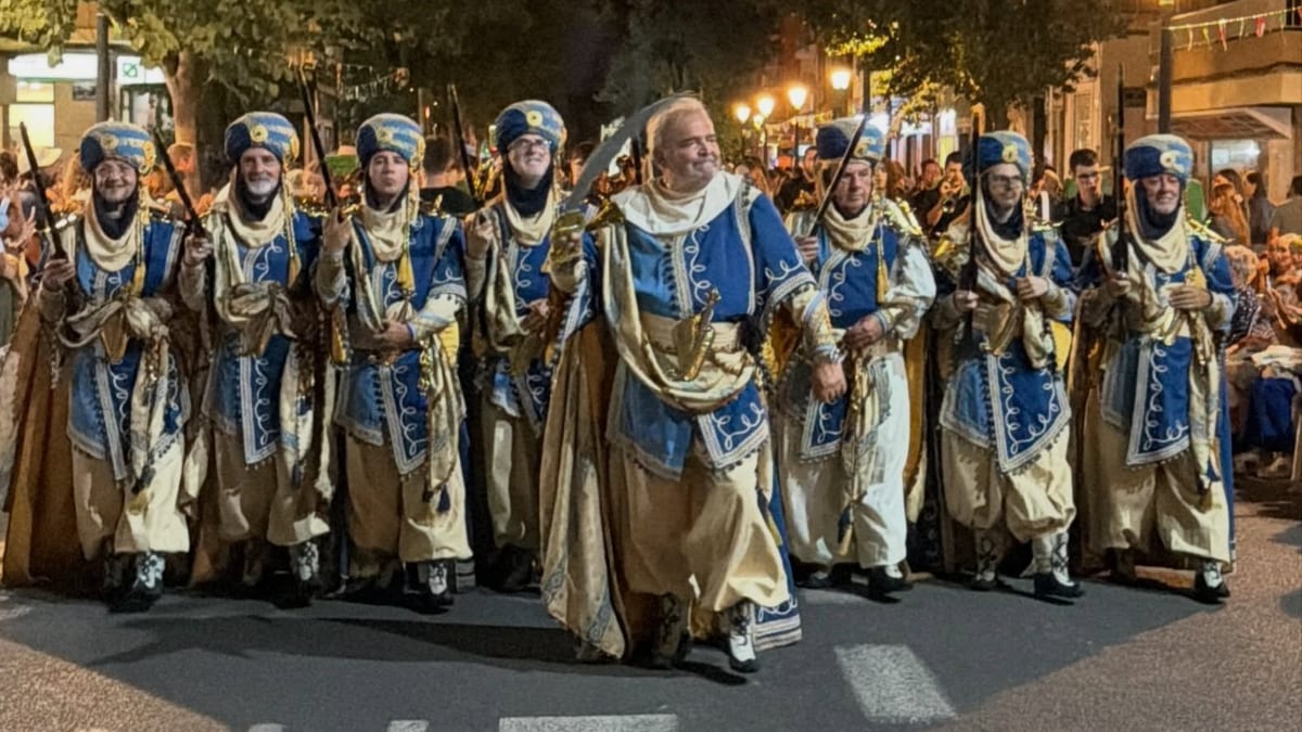 Procesión nocturna de participantes en trajes tradicionales azules y beige durante la XXX Entrada de Moros y Cristianos del Marítimo en Valencia
