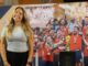 Mujer posando frente a mural del equipo de fútbol español con Copa del Mundo