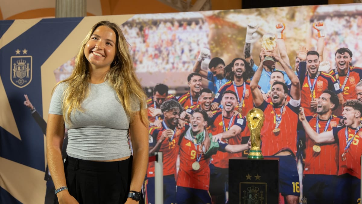 Mujer posando frente a mural del equipo de fútbol español con Copa del Mundo