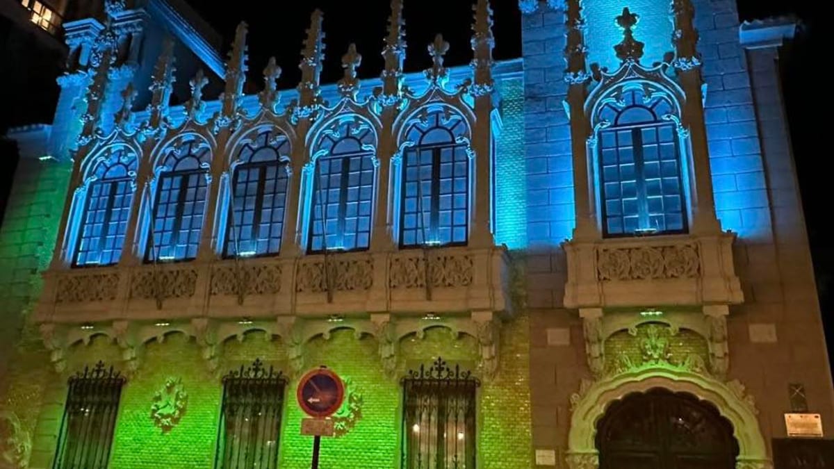 Fachada gótica del edificio municipal de Albacete iluminada con luces azules y verdes durante la noche para concienciar sobre la Hipertensión Intracraneal Idiopática