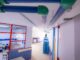 Corredor interior de un centro educativo con instalaciones de climatización y tuberías verdes en el techo